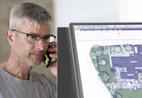 Beratungsgespräch mit einem Kunden anhand eines digitalen Gartenplans.