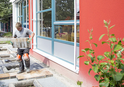 Mitarbeiter bei der Ausführung von Pflasterarbeiten in einem Kindergarten in Benhausen.