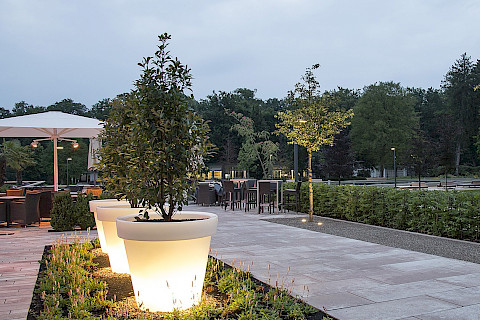 Lichtinszenierung einer Gastronomieterrasse mit Baumbeleuchtung und leuchtenden Pflanzgefäßen im Parkhotel Bad Lippspringe.