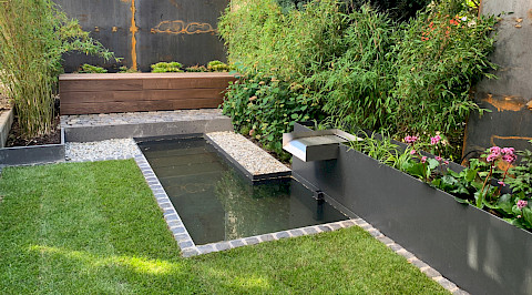 Kleiner Stadtgarten mit individuell gefertigten Metallelementen und Wasserbecken in Paderborn.
