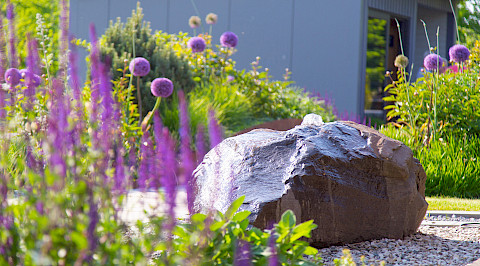 Quellstein mit Staudenbepflanzung in einem Privatgarten in Borchen.